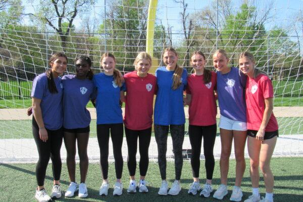 Quincy Notre Dame female students pose for a photo outdoors during Raider Cup in their colorful House shirts.