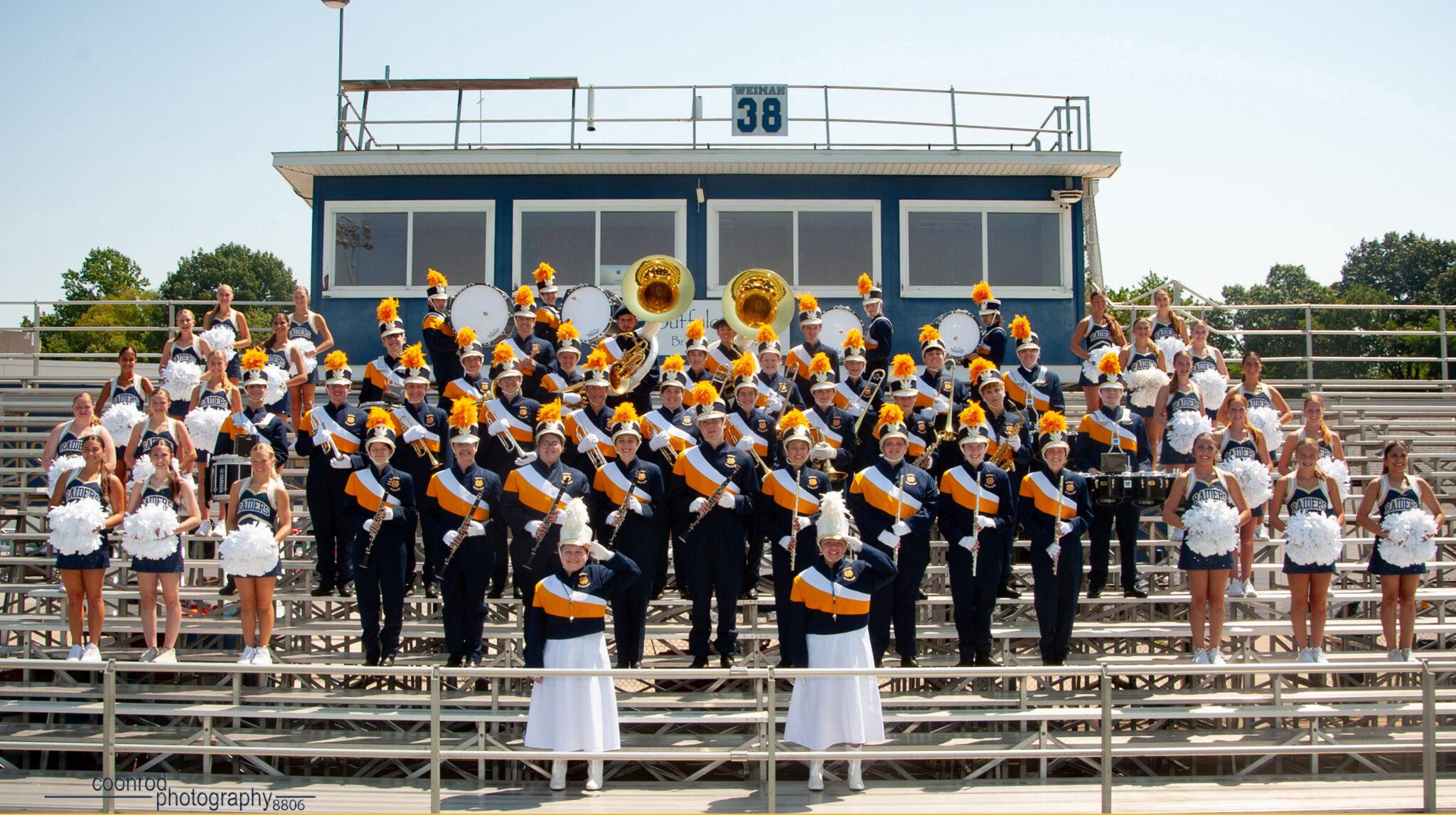 QND band and pommers poses for photo on bleachers outdoors.