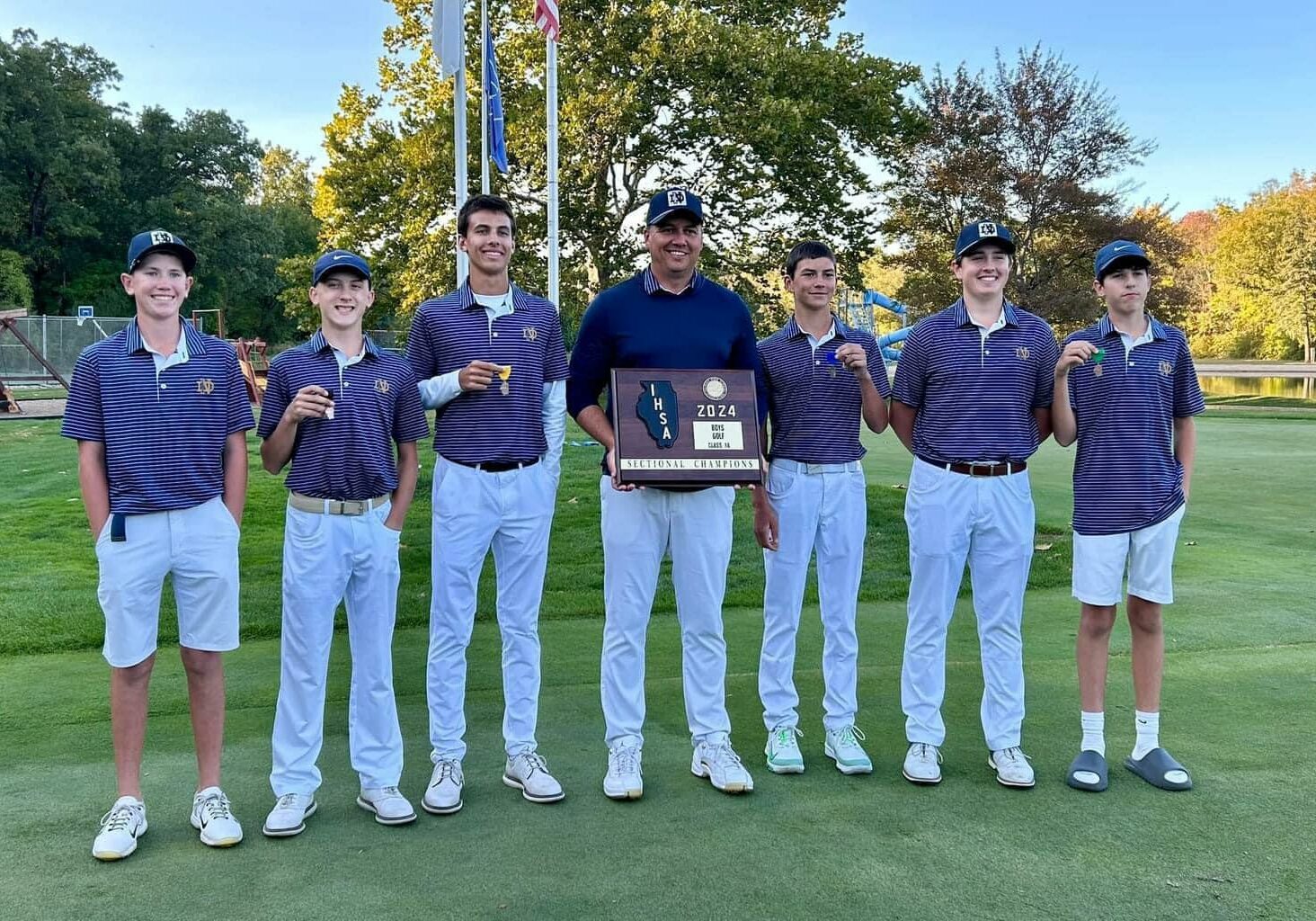 Quincy Notre Dame boys golf team celebrating 2024 sectional championship win with trophy on the course.