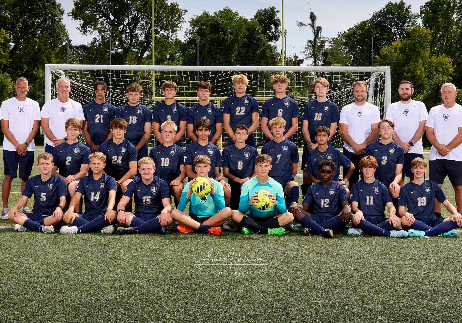 Quincy Notre Dame boys soccer team posing for 2024 season photo on the field in uniform.