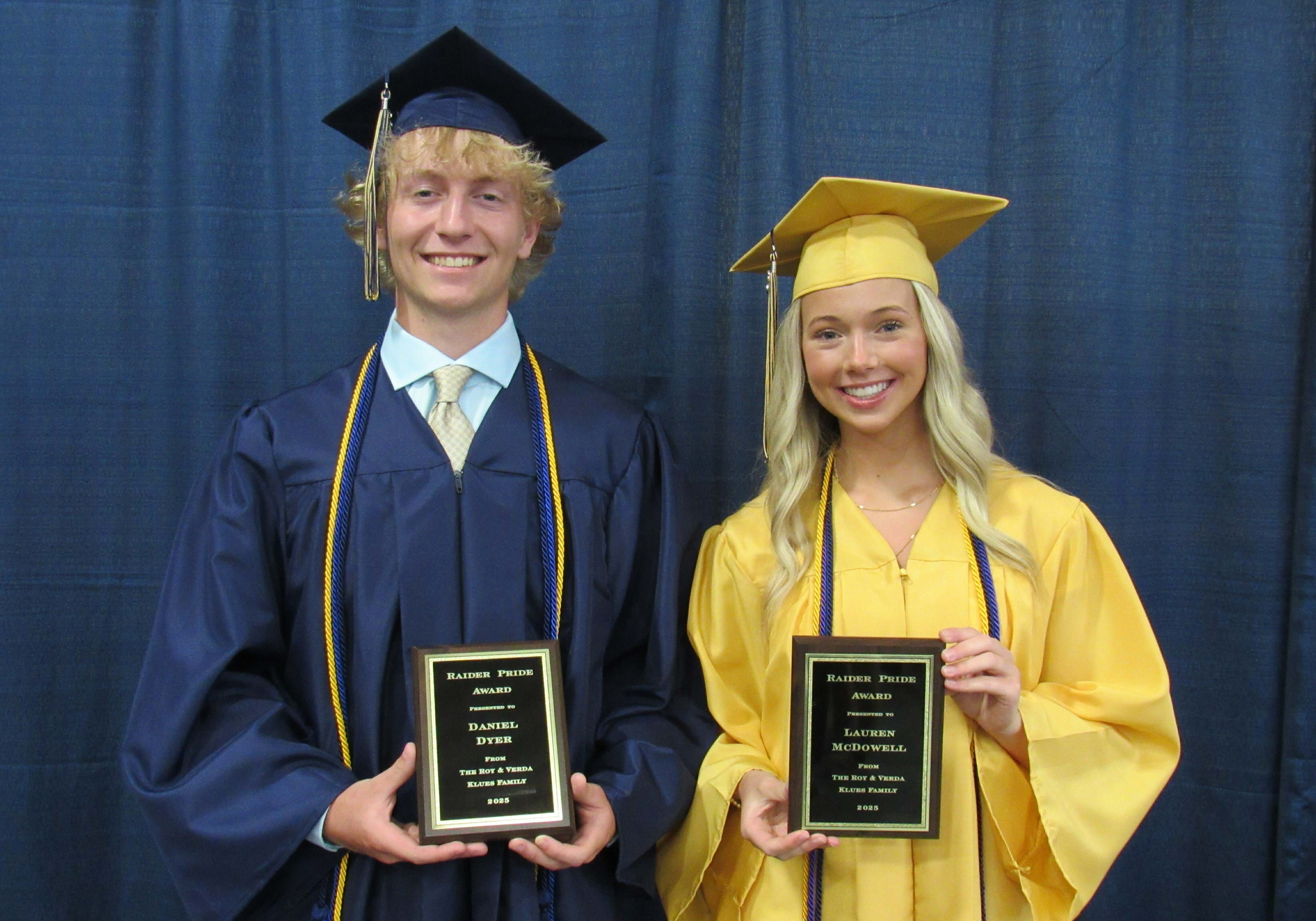 Quincy Notre Dame students holding Raider Pride Award certificates, smiling for a photo in front of a school banner.