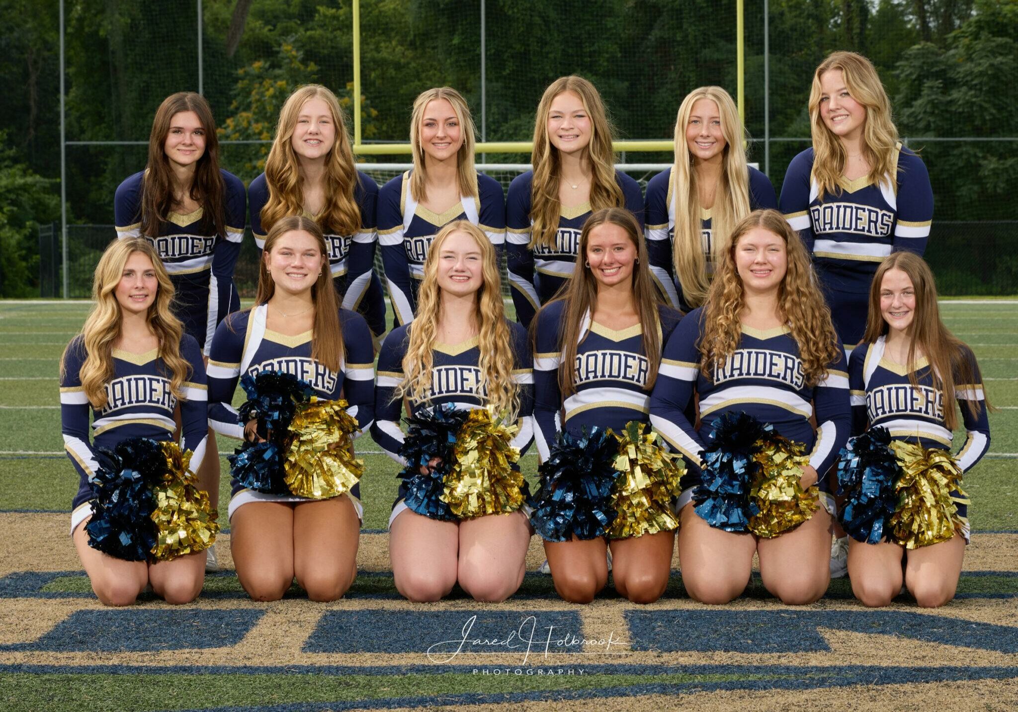 2024-25 Quincy Notre Dame varsity cheerleading squad posing in uniform on the football field.