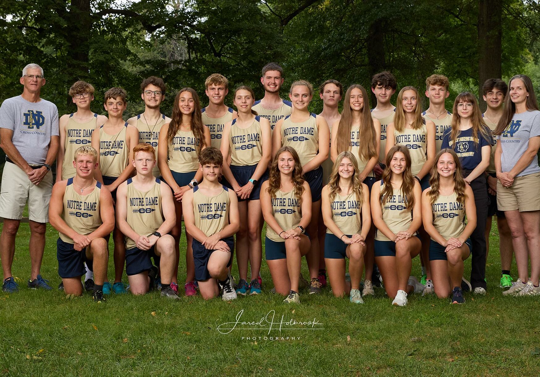 Quincy Notre Dame cross country team group photo outdoors, with athletes in team uniforms.